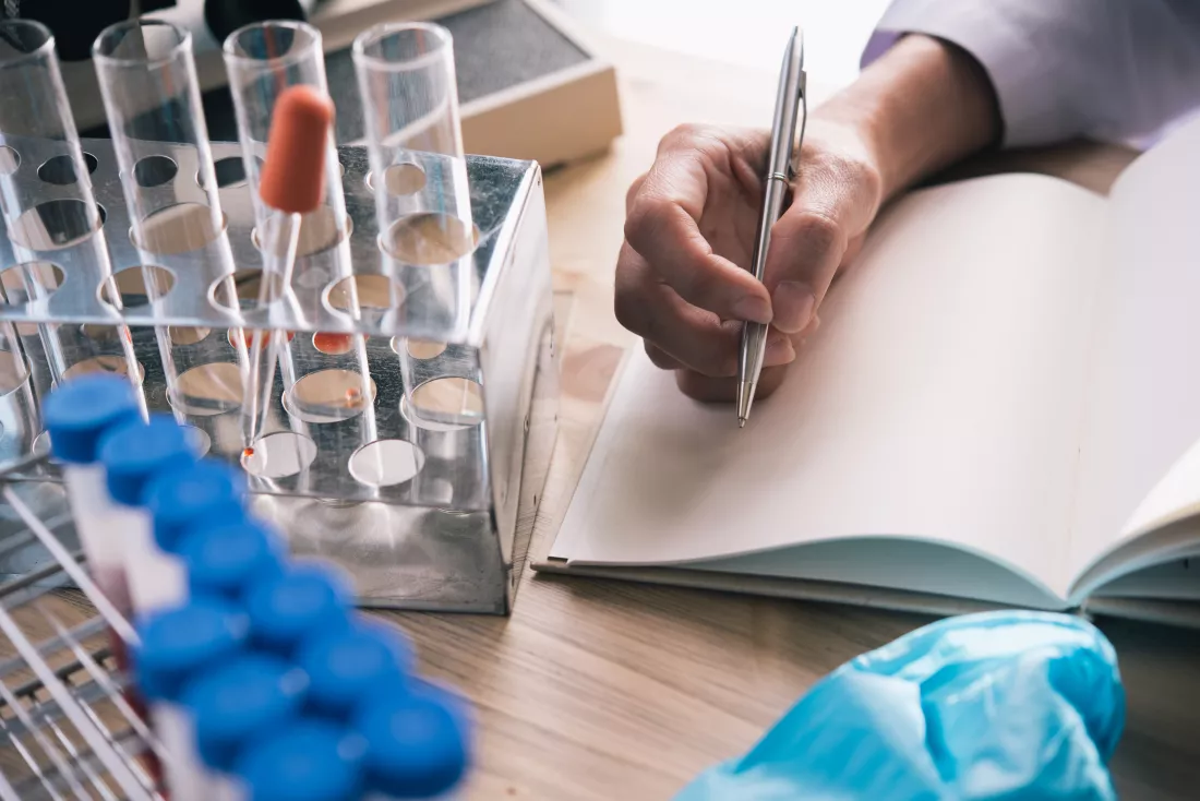 cropped-hand-scientist-writing-book-desk