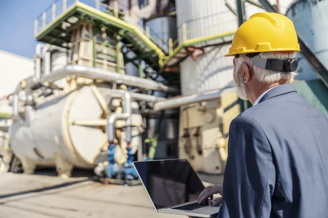 rear-view-senior-businessman-with-helmet-his-head-holding-laptop
